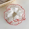 Nahaufnahme von weißem Spitzen-Haargummi mit rotem Stickrand und Blumenmuster-Details - Roter Muschelsaum Blumenstil