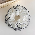 Detailaufnahme von weißem Blumen-Scrunchie mit blauem Muster und Wellenrand auf Cremegrund - Blauer Muschelsaum Blumenstil