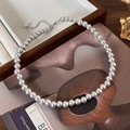 Dettaglio collana di perle grigie con catena regolabile su vassoio estetico - Stile 8mm
