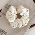 Dettaglio di un elastico per capelli in raso a pois imbottito su lino vintage - Bianco con pois neri