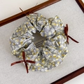 Details des grauen Blumen-Scrunchies mit gelben Mustern und braunen Satinschleifen - Gelbgrau Rund Stil