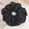 Vue détaillée du grand chouchou en maille noire à pois blancs sur tissu en lin naturel - Grand / Noir Pois Blancs