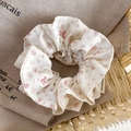 Detaillierte Nahaufnahme des weißen Blumen-Scrunchies mit handgefertigtem gewebtem Etikett - Cremeweiß Blumen Bogen Stil