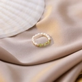 Detail view of pearl beaded ring with green gemstones on champagne silk fabric - Green