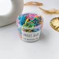 Overhead view of colorful children's hair ties in a clear jar with minimal props - Spring Colors