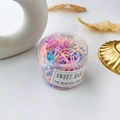 Close-up of colorful disposable hair elastics for girls in a clear cylinder storage jar - Jelly Color