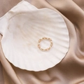 Détail d'une bague artisanale avec perles et cristaux sur un tissu en soie champagne - Rose