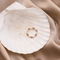 Détail d'une bague artisanale avec perles d'eau douce et cristaux violets sur un coquillage - Violet