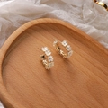 Dettaglio di orecchini a cerchio dorati a forma di C con fiori di conchiglia su vassoio in legno - Stile Petalo Bianco a Forma di C Oro