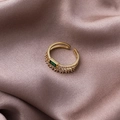Detailaufnahme des doppellagigen Goldrings mit smaragdgrünem Zirkon auf Seidensatin - Gold (Grüner Edelstein Stil)