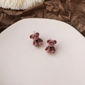 Details von rosa-braunen beflockten Bären-Ohrringen mit schwarzer Schleife auf Keramik - Rosa