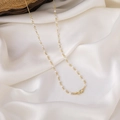 Detalle de una cadena dorada con pequeñas perlas blancas sobre fondo de seda blanca - Estilo de Cadena de Perlas