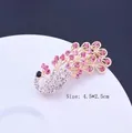 Eleganter Pfauenbrosche-Anstecker mit funkelnden rosa und weißen Kristallen auf Gold - Rosa