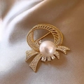 Elegante spilla a fiocco dorata con perla bianca e cristalli su sfondo di raso - Stile Perla Anello Fiocco