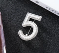 Spilla argentata numero 5 con perle finte bianche e cristalli su sfondo nero opaco - Argento
