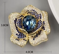 Dettaglio della spilla a camelia in cristallo con una grande gemma blu a forma di goccia - Blu scuro