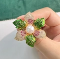 Spilla floreale elegante con perla centrale e foglie in smalto verde indossata sulla mano - Forma di Fiore (T0255)