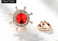 Macro view of 1.9cm rose gold rudder brooch with red gemstone and white rhinestones - Ship Helm (X0234) / 1.9cm x 1.9cm / Red