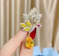 Dettaglio di una spilla floreale dorata con cristalli gialli e accenti rosa fine - Giallo