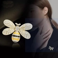 Broche de abeja dorada con cristales brillantes y esmalte amarillo sobre fondo oscuro - Dorado