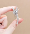 Detailansicht der silbernen Bambus-Brosche mit funkelnden Kristallen in der Hand - Bambusknoten Form / Silber