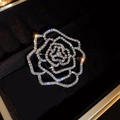 Detailed view of silver camellia brooch with sparkling rhinestones and hollow design - Silver