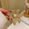 Elegant maple leaf brooch with sparkling pavé crystals and a central white pearl inlay - Gold