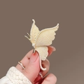 Eleganter Schmetterlings-Brosche mit Perlen in Goldoptik, Nahaufnahme in der Hand - Schmetterling Perle Stil