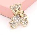 Detalle de un broche de oso dorado brillante con pedrería transparente y lazo de decoración - Dorado