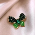 Elegante broche de mariposa con cristales verdes y borde dorado sobre seda de champán - Mariposa Verde