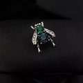 Spilla ape vintage con cristalli color smeraldo e blu navy su sfondo in pelle scura - verde scuro