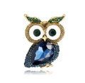 Macro shot of owl brooch with blue crystal and green rhinestone detailing on gold alloy - Blue