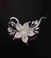 Detalle de broche de flor plateada con perla blanca central y circonitas brillantes - Plateado