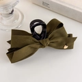 Détail de la pince à cheveux en velours vert olive avec cœur doré sur une table blanche - Vert