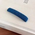 Detail of dark blue tweed textured minimalist hair clip on an open book cover - Blue