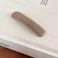 Close-up of a brown knitted barrette showing soft woven texture on a book background - Light Coffee