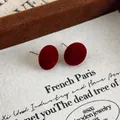 Close-up of red flocked round stud earrings with vintage French style and soft velvet texture - Red