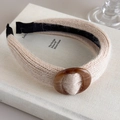 Dettaglio fascia per capelli in maglia beige con fibbia in resina ambrata su libri - Beige