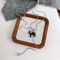 Detail of silver snake chain with black horse pendant and star charm on sweater - Black (27608C)
