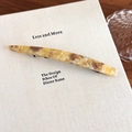Detail of tortoiseshell acetate hair clip with a gold metal emblem on an aesthetic book - Yellow Multi-color (27606C)