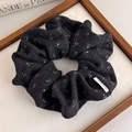 Detailansicht eines dunklen Blumen-Scrunchies mit gebürsteter Textur und weißen Blumen - Schwarz