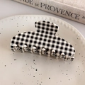 Gros plan d'une grande pince à cheveux à carreaux noir et blanc sur un plateau - Grille Noir Blanc