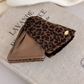 Detail der Haarklammer mit Leopardenmuster, braunem Lederfutter und goldenem Logo-Anhänger - Kaffee Leoparden-Patchwork