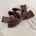Détail d'un nœud vintage marron en maille avec pendentif doré sur un décor de livre rétro - Café