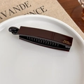 Makro-Detail der dunkelbraunen Bananen-Haarklammer mit goldenem Barrette La France-Schriftzug - Dunkelbraun