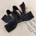 Détail d'une pince banane à nœud tricoté noir avec pendentif doré sur un livre - Noir