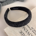 Detail of dark grey felt headband showing handmade woven label and soft fiber texture - Black