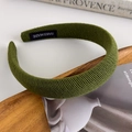 Detailed view of olive green knitted headband with handmade label on wooden tray - Olive Green