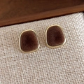 Detailed macro view of vintage square velvet stud earrings with golden metal edging - Brown Trapezoid