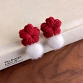 Detail von roten gestrickten Blumenohrringen mit weißen Kunstfellbommeln und Wolltextur - Rote Blume